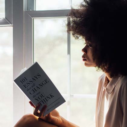 Woman sitting by the window and reading a novel